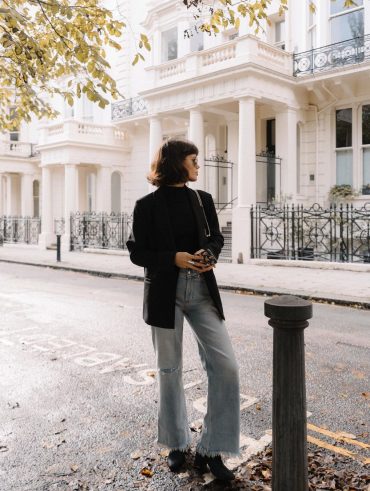 Chloe Miles com corte de cabelo french bob, usando jeans e blazer preto