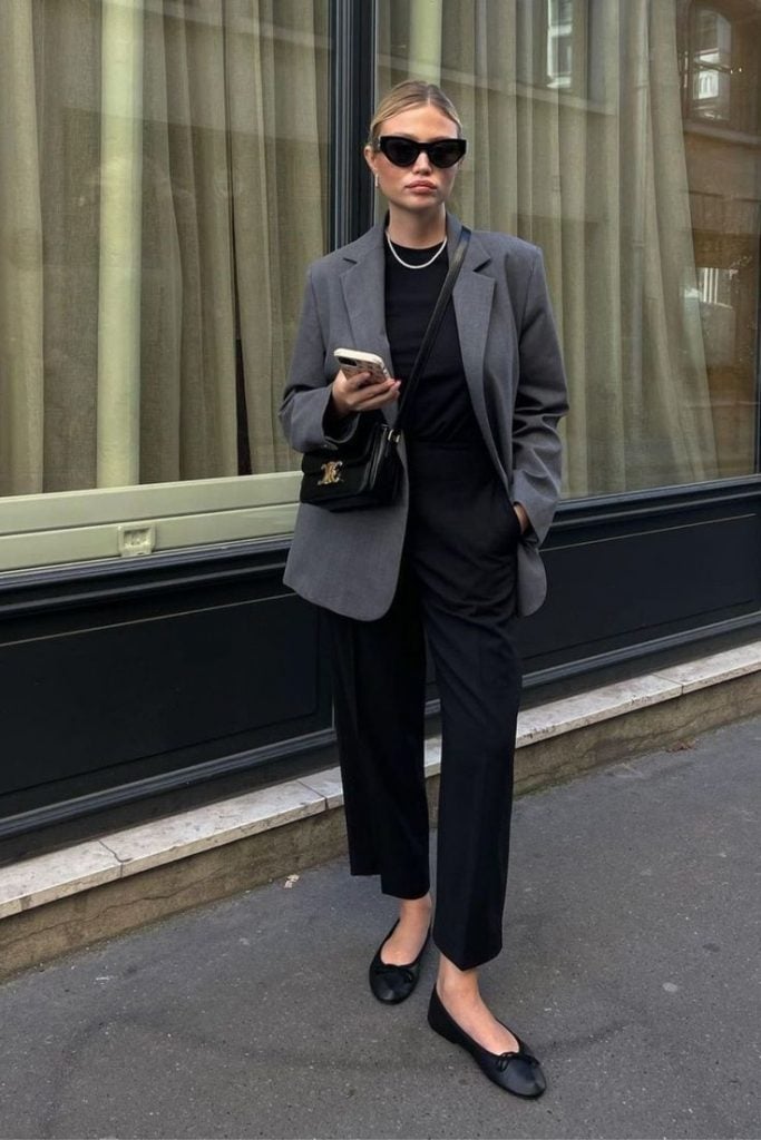Marine Diet com blazer cinza, blusa básica preta, calça de alfaiataria preta e sapatilha preta