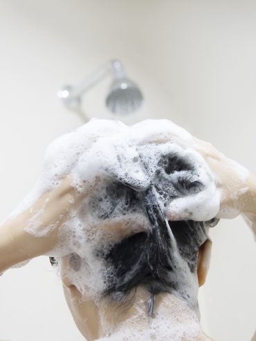 Mulher lavando o cabelo com shampoo e condicionador