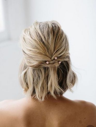 Mulher branca, com cabelo loiro, com penteado semipreso atrás, com pérolas