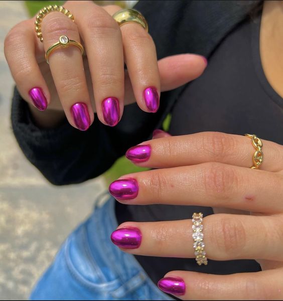 Mãos brancas com anéis e unha curta rosa metalizada