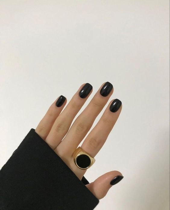 Mão branca com anel preto e unha quadrada curta preta