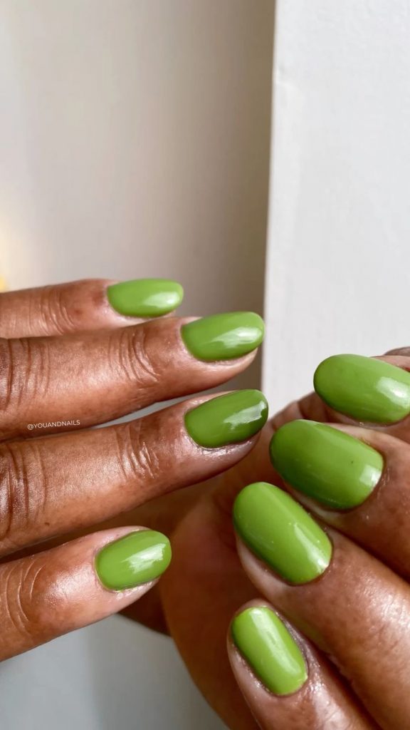 Mão negra com unha curta arredondada com esmalte verde folha
