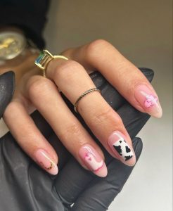 Mão branca com anel apoiada em outra mão, com as unhas amendoadas estilo cowgirl