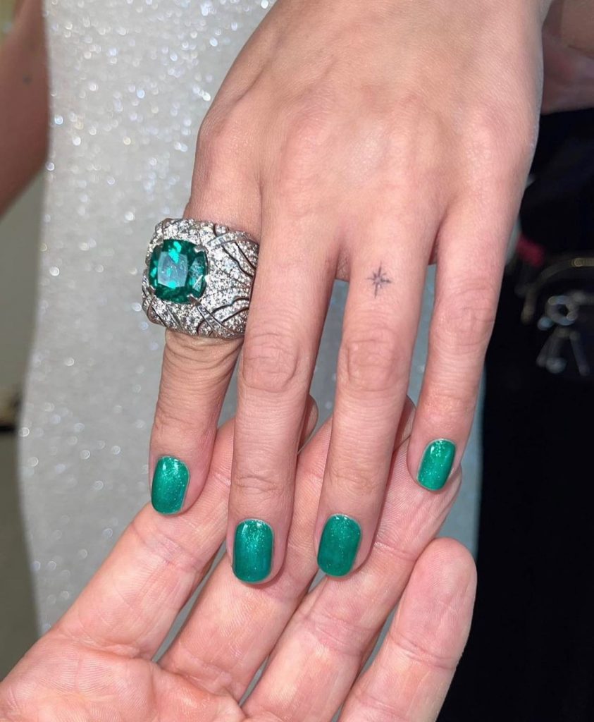 Mão branca com anel brilhante e unha curta verde esmeralda com brilho 