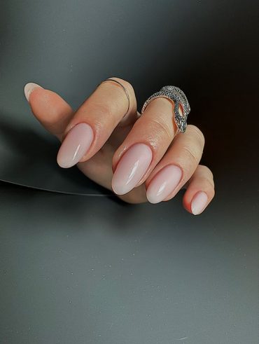 Mão branca curvada com anéis e unha amendoada natural