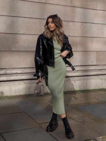 Mulher usando jaqueta de couro com vestido longo em cor verde e calçando coturno.