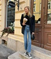 Mulher jovem usando blazer, calça jeans e tênis