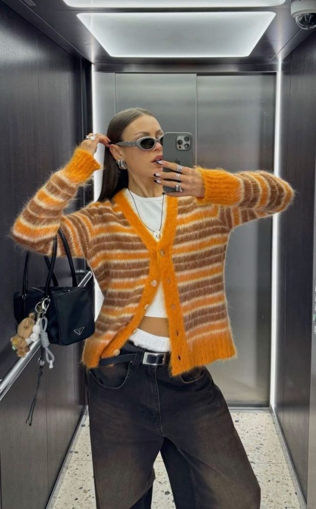 Mulher jovem de pele clara e cabelos castanhos e lisos. Ela usa look com estampa listrada.