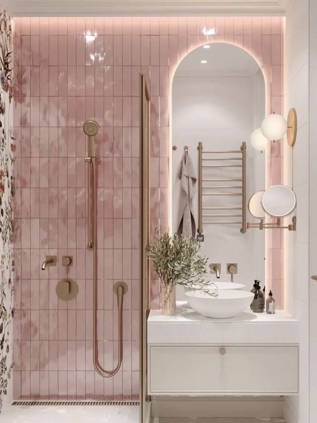Banheiro com azulejos rosas e louças brancas, com detalhes em rose gold