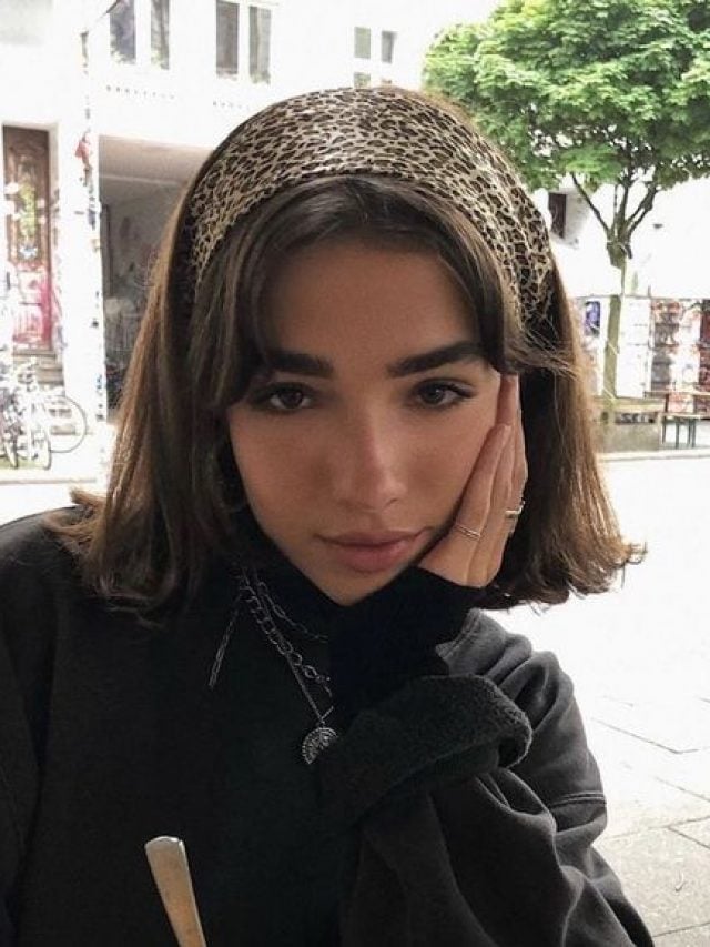 Mulher branca com corte de cabelo curto e faixa com estampa de oncinha