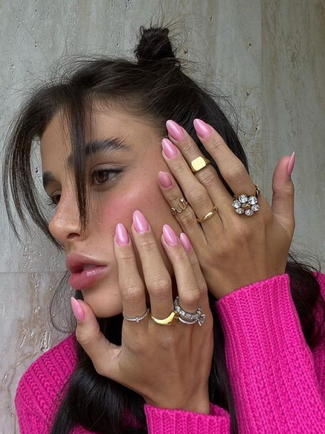 Livia Nunes com as maõs apoiadas no rosto com a unha amendoada rosa perolada