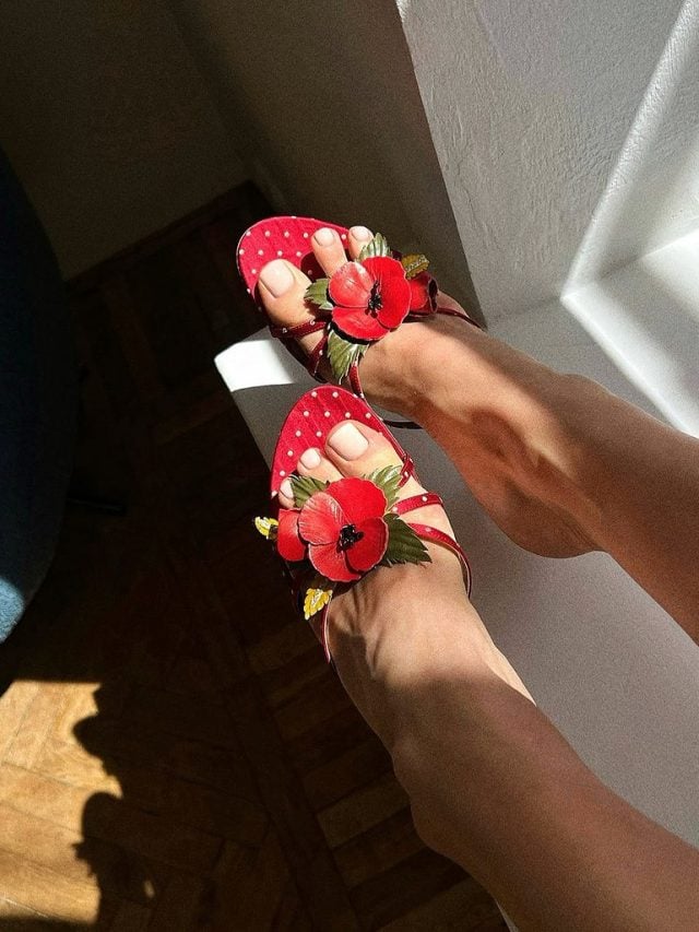 Pés brancos com unha neutra e sapato vermelho de flor