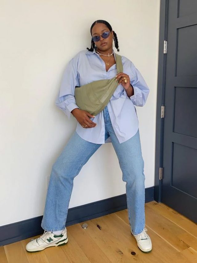 Mulher jovem de pele negra. Ela usa camisa azul, calça jeans e tênis