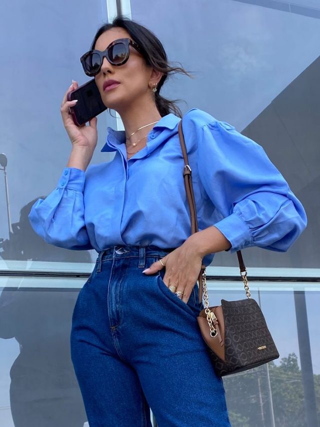 Mulher usando camisa de manga bufante em cor azul e calça jeans.