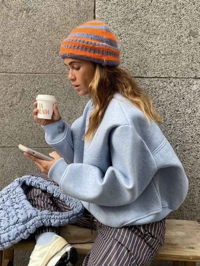 Mulher jovem e de pele clara usando moletom azul bebe.