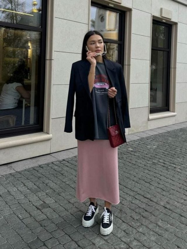 mulher jovem usando camiseta e saia de cetim rosa com tênis.