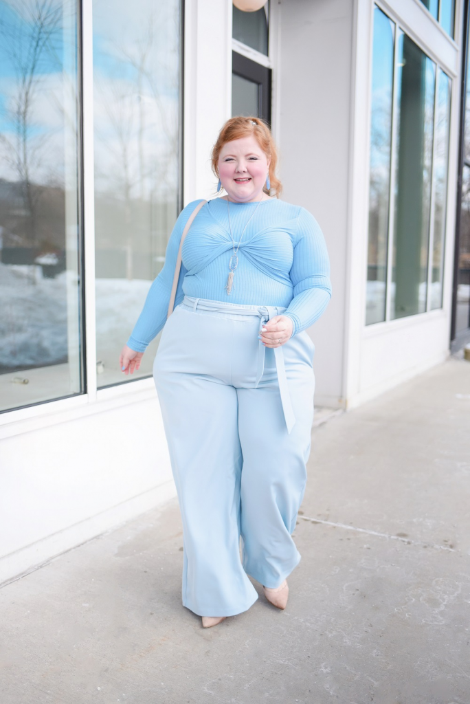 Mulher jovem e gorda, usando básica de manga longa em cor azul claro e calça em azul bebê.