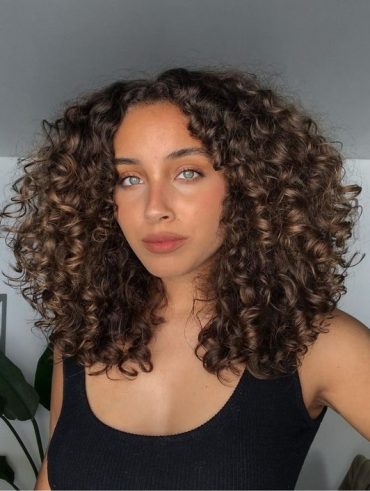 Mulher com cabelo cacheado, iluminado no tom chocolate
