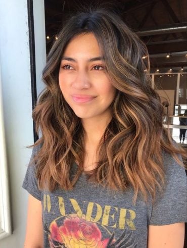 Mulher com cabelo médio, com mechas no tom caramelo com técnica balayage