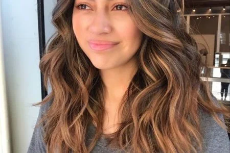 Mulher com cabelo médio, com mechas no tom caramelo com técnica balayage