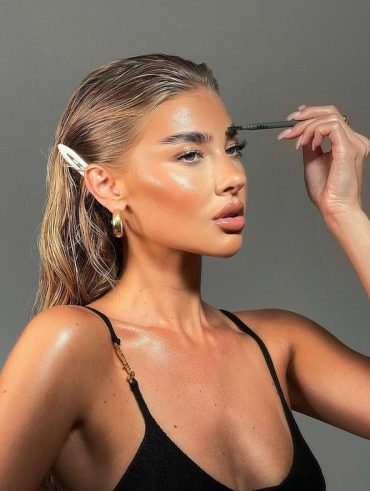 Mulher branca com blusa de regata preta, presilha no cabelo e maquiagem simples