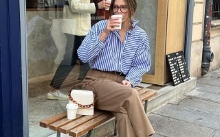 Elodie Romy usando camisa listrada azul, calça de alfaiataria reta, bolsa off-white e loafer bicolor