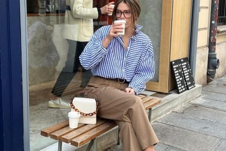 Elodie Romy usando camisa listrada azul, calça de alfaiataria reta, bolsa off-white e loafer bicolor
