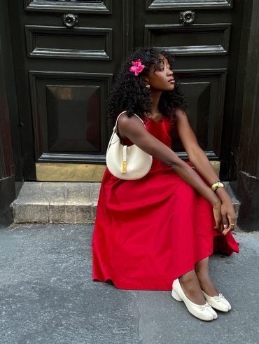 Emmanuelle Koffi usando vestido midi vermelho romântico, bracelete dourado, sapato Tabi branco e shoulder bag branca