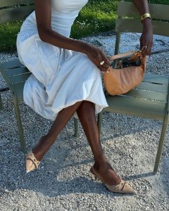 Emmanuelle Koffi usando vestido branco romântico, bolsa caramelo e mule caramelo de scarpin