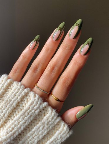Mão branca com anéis e unha amendoada verde com decoração de laço