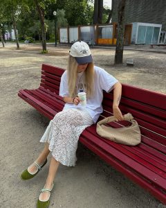 Julia usando saia de renda branca, boné, camiseta divertida e sapatilha de veludo