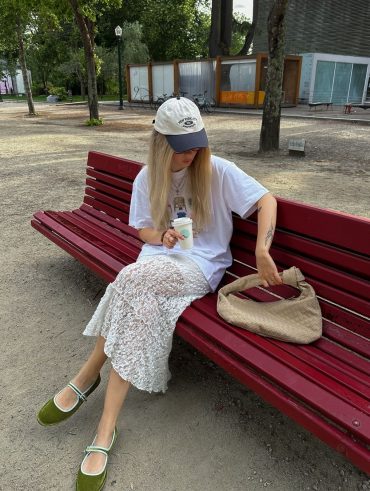 Julia usando saia de renda branca, boné, camiseta divertida e sapatilha de veludo