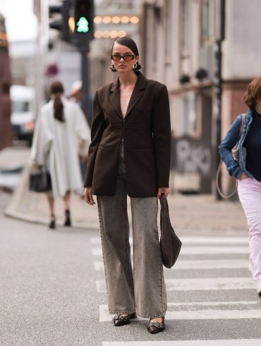 Mary usando óculos de sol de lente transparente colorida, blazer oversized marrom, calça jeans pantalona e slingback Ganni