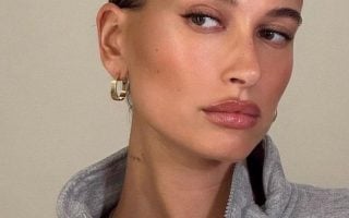 Hailey Bieber com casaco cinza e maquiagem natural
