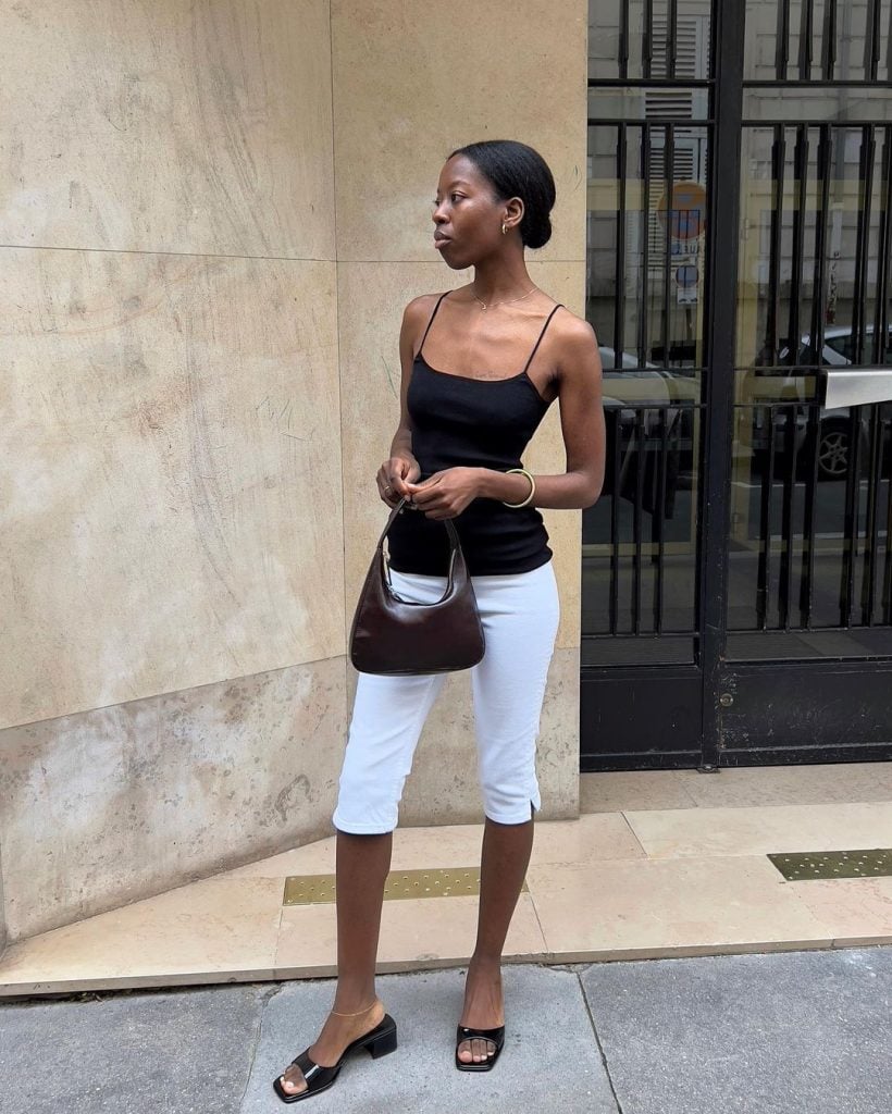 Sylvie Mus usando blusa preta de alça, calça capri branca, shoulder bag minimalista marrom e tamanco