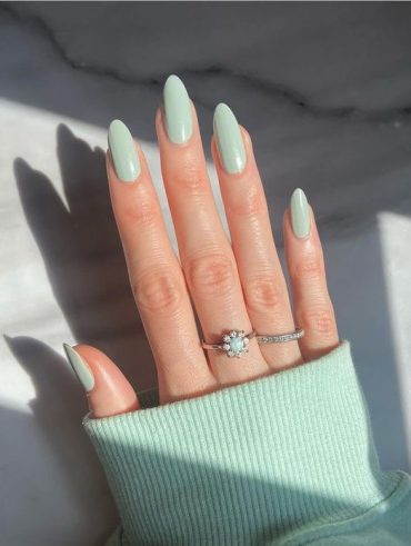 Mão branca com anéis e unha arredondada verde-menta