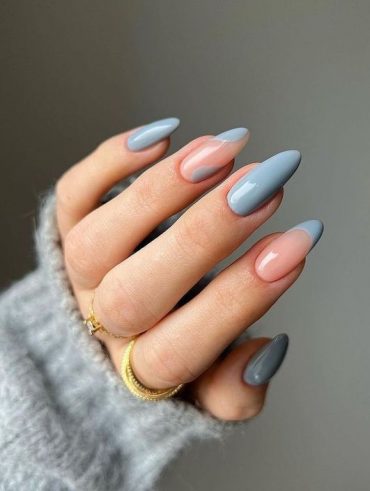 Mão branca curvada com anéis e unha amendoada azul-claro acizentado