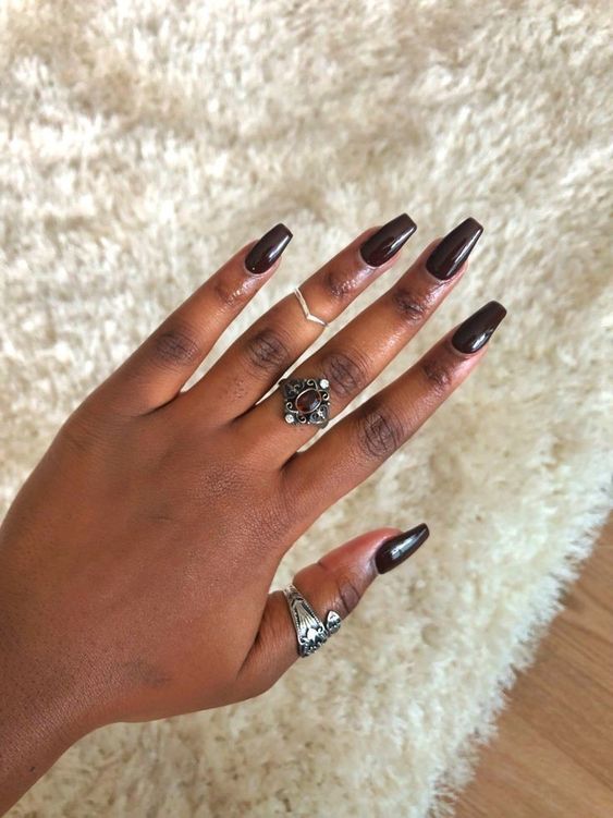 Mão negra com anéis prata e unha marrom escuro