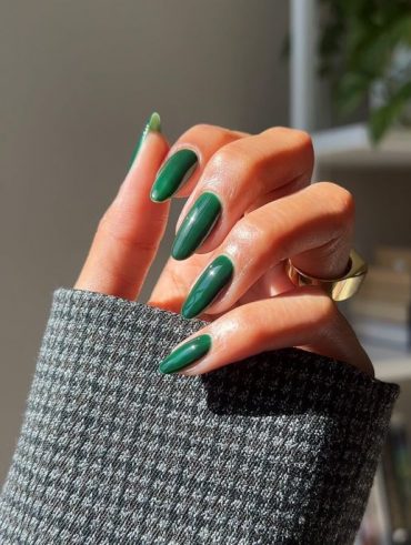 Mão branca curvada com unha comprida verde escuro