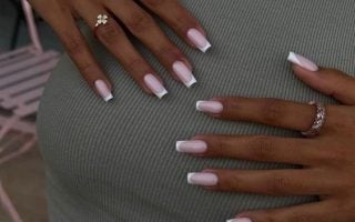 Mãos brancas com anéis, apoiadas no corpo com unha quadrada francesinha
