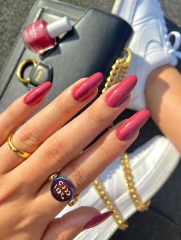 Mão branca com anéis e unha amendoada rosa escuro