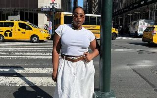 Mulher jovem e midsize com camiseta e saia branca e cinto marrom.