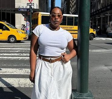 Mulher jovem e midsize com camiseta e saia branca e cinto marrom.