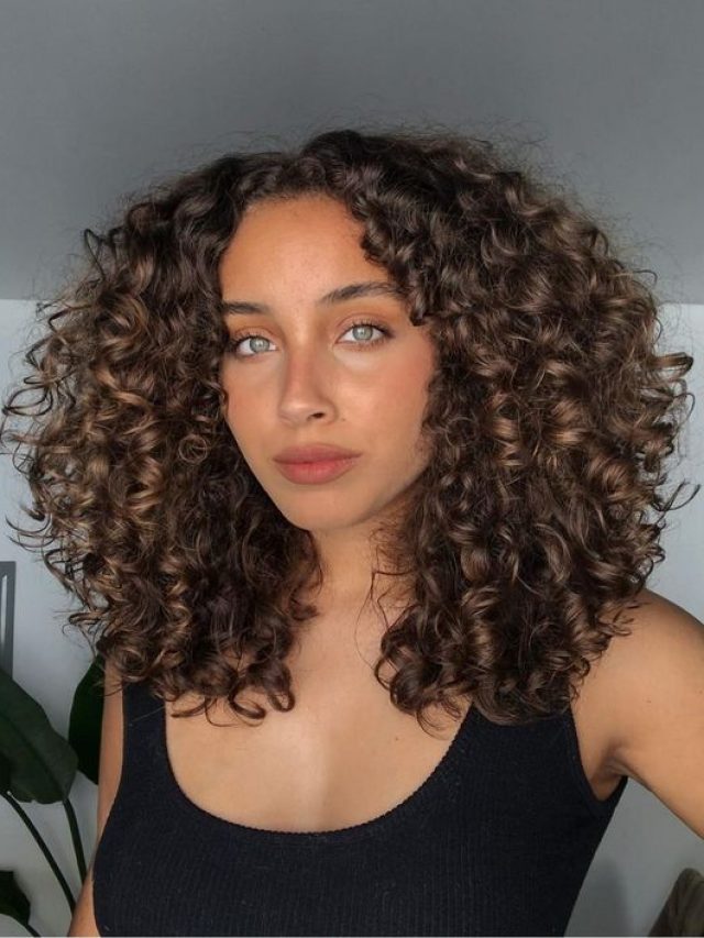 Mulher com cabelo cacheado, iluminado no tom chocolate