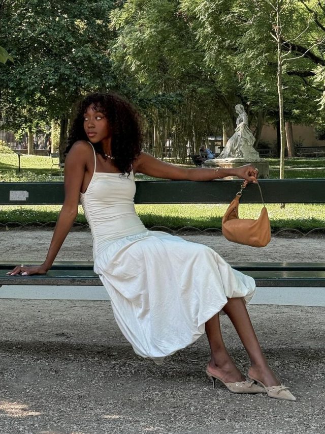 Emmanuelle Koffi usando vestido branco romântico, bolsa caramelo e mule caramelo de scarpin