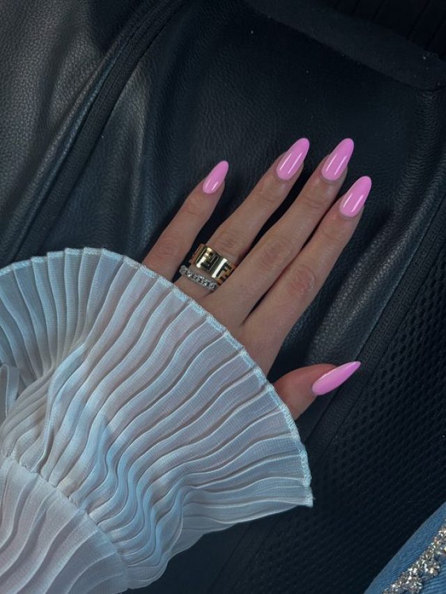 Mão branca com anel e unha amendoada rosa chiclete