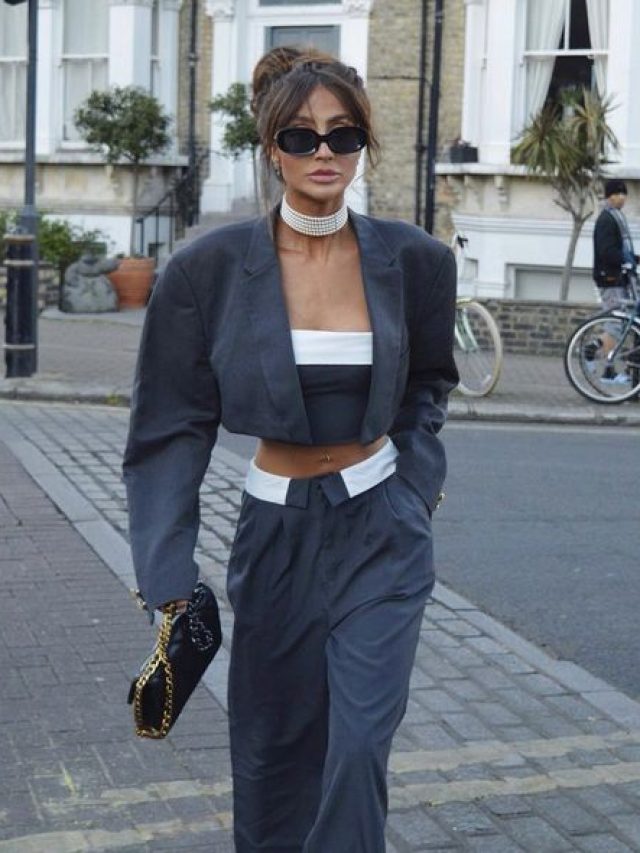 Mulher jovem e magra com pele clara. Ela usa blazer cropped e calça em alfaiataria.