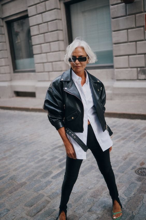 Mulher de meia idade com jaqueta de couro preta, camisa branca e legging