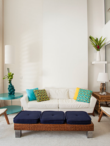 Sala de estar branca com sofá a poltronas brancos e almofadas coloridas